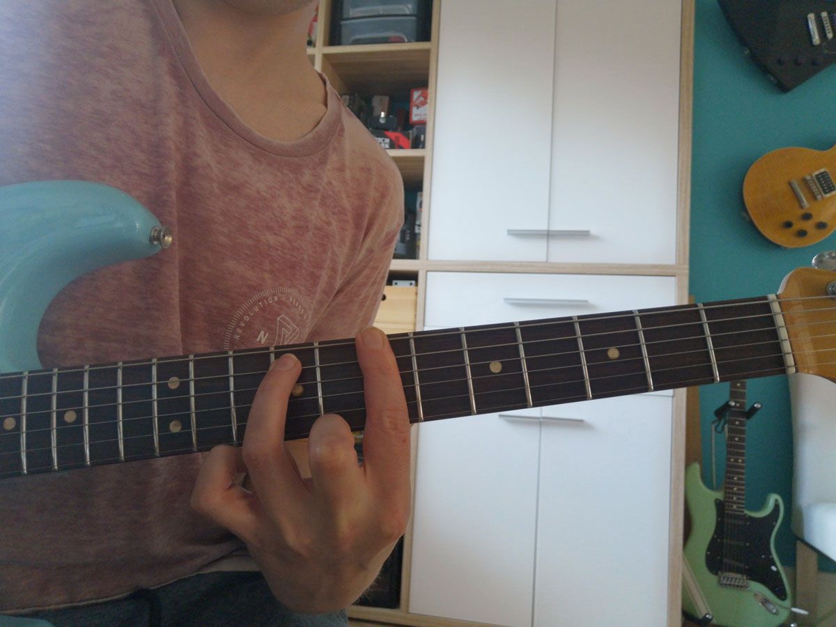 A person playing the Bm7 E shape barre chord on electric guitar