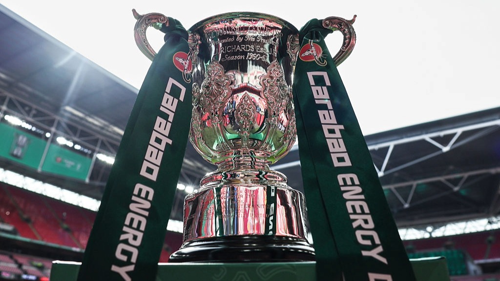 A shot of the Carabao Cup, with green ribbons, with Wembley Stadium in the background.