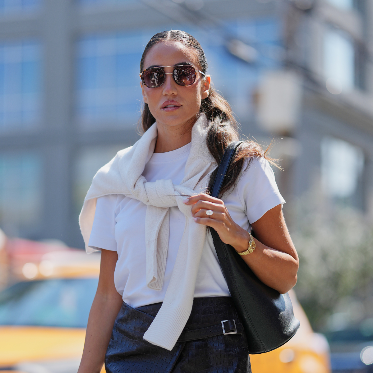 Encapsulated SPF Tamara Kalinic wears center-parted long brown hair pulled back into a low ponytail with loose waves, dark aviator sunglasses, a black leather cuff on one wrist 