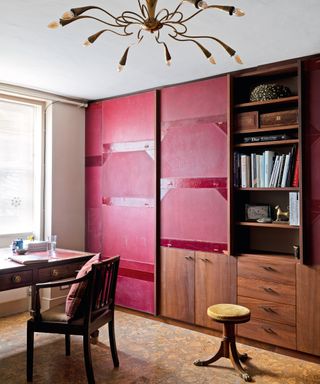 home office with vintage red leather folio bookcase, statement pendant and wooden table and chair