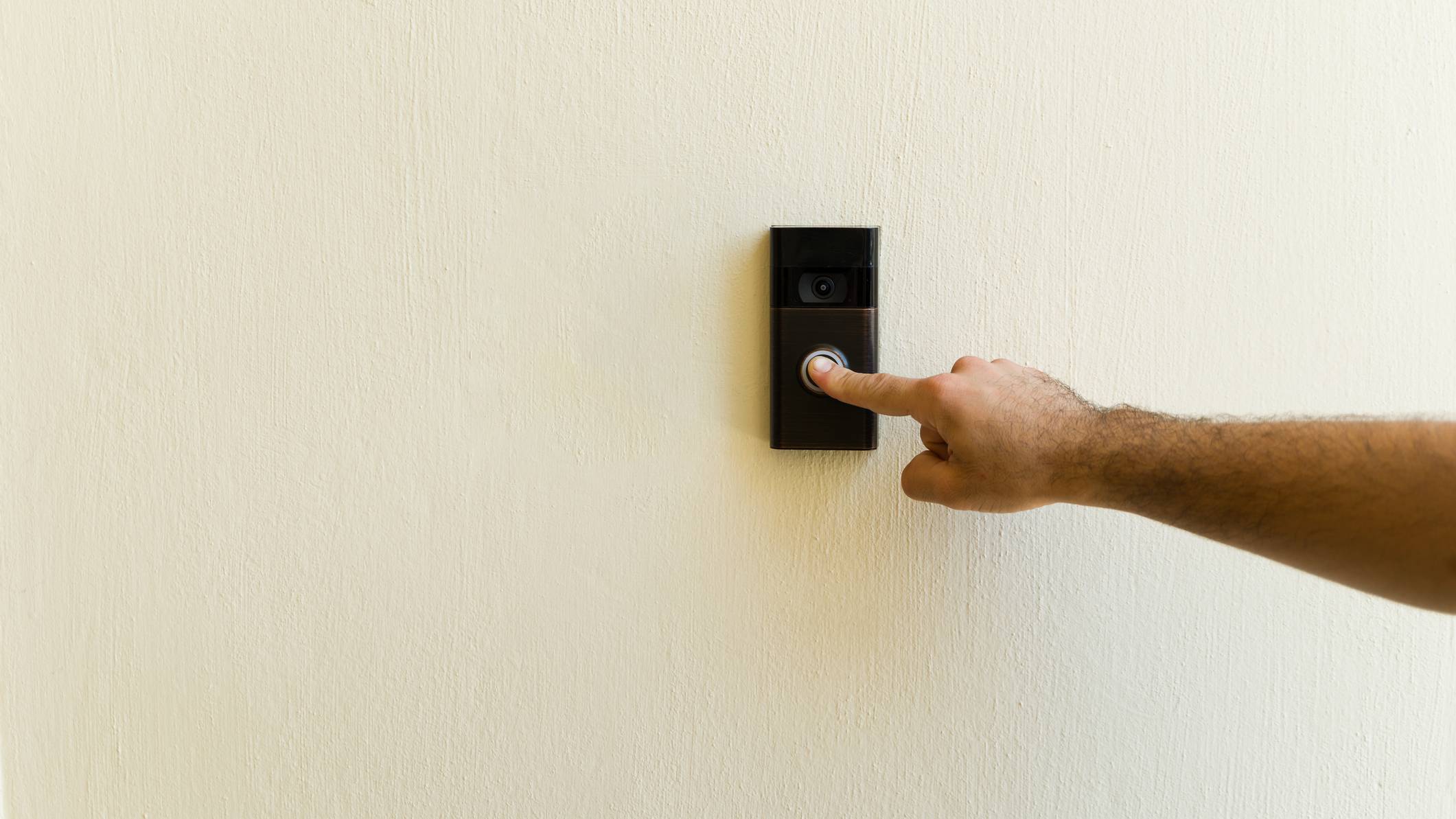 A hand pressing the button on a Ring video doorbell