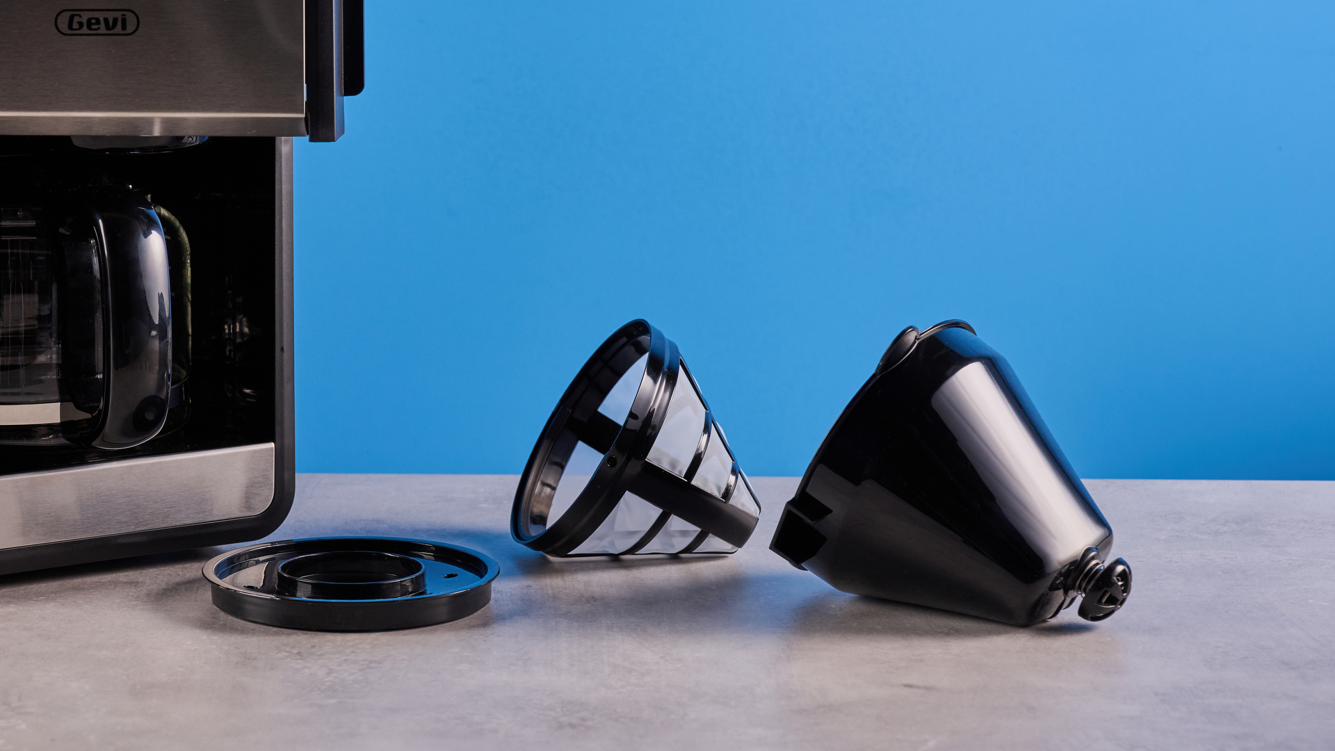 the gevi 10-cup drip coffee maker with grinder photographed against a blue background, showing the glass carafe, water tank, touch screen, and accessories including plastic filter