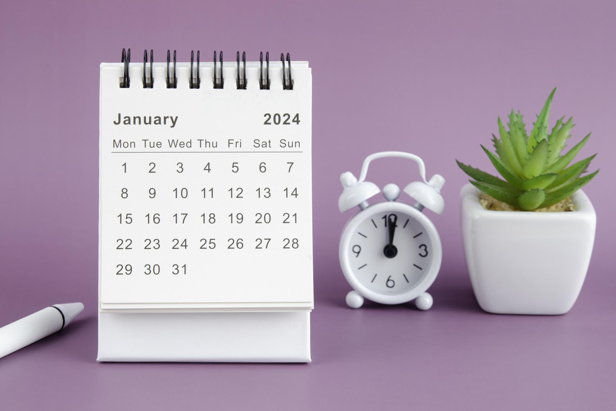  A calendar displaying the month of January in 2024. With a white alarm clock and a small plant on a purple background. 