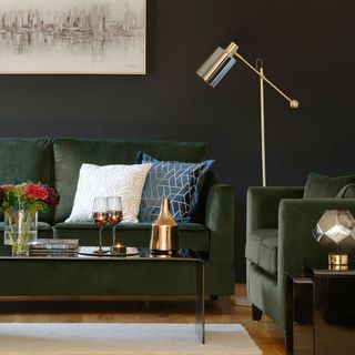 dark green velvet sofas in green living room with coffee table and brass lamp