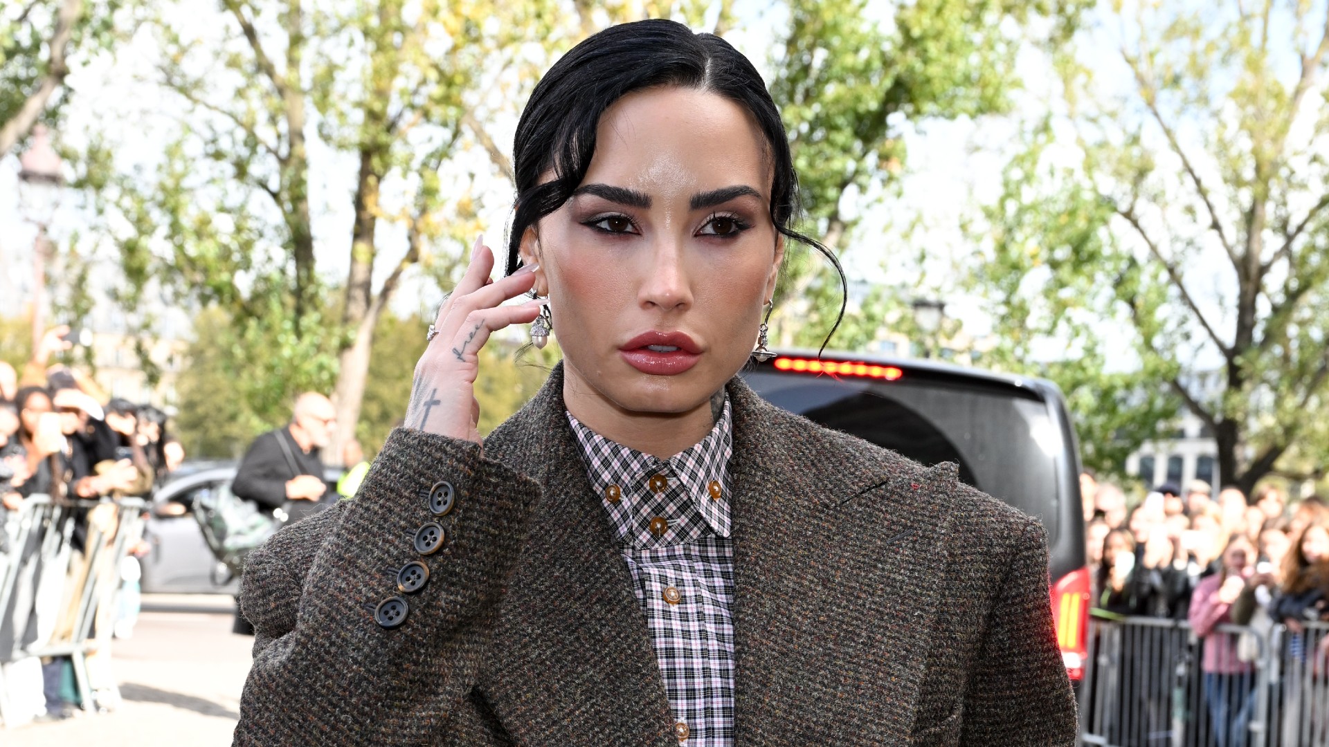 a white woman with black hair pulled into a bun being photographed by paparazzi