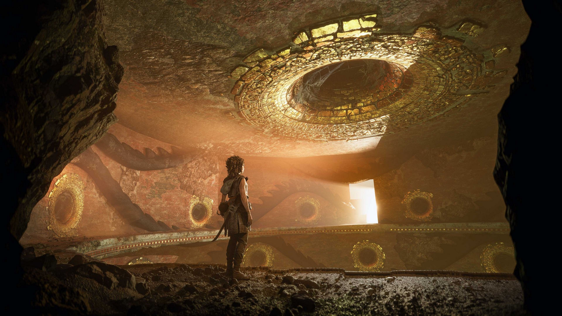 Sophia stands on a balcony-like ledge within a temple in Resonance: A Plague Tale Legacy, the walls and ceiling marked with curved halls with a gold trim