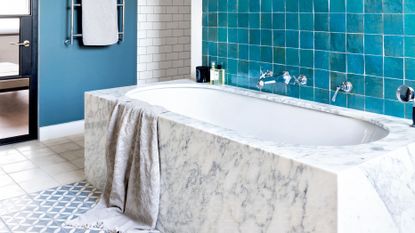 An example of modern bathroom ideas showing a marble bath next to blue wall tiles