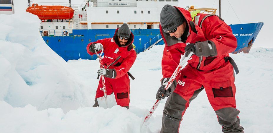 stranded icebreaker crew prepares spot for landing helicopter