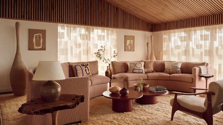 A peige sofa, curved and made up of two modular sections, in a contemporary living room