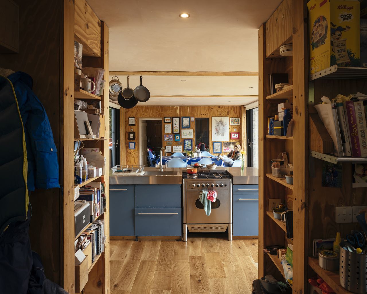 blue kitchen with stove in open plan timber clad room