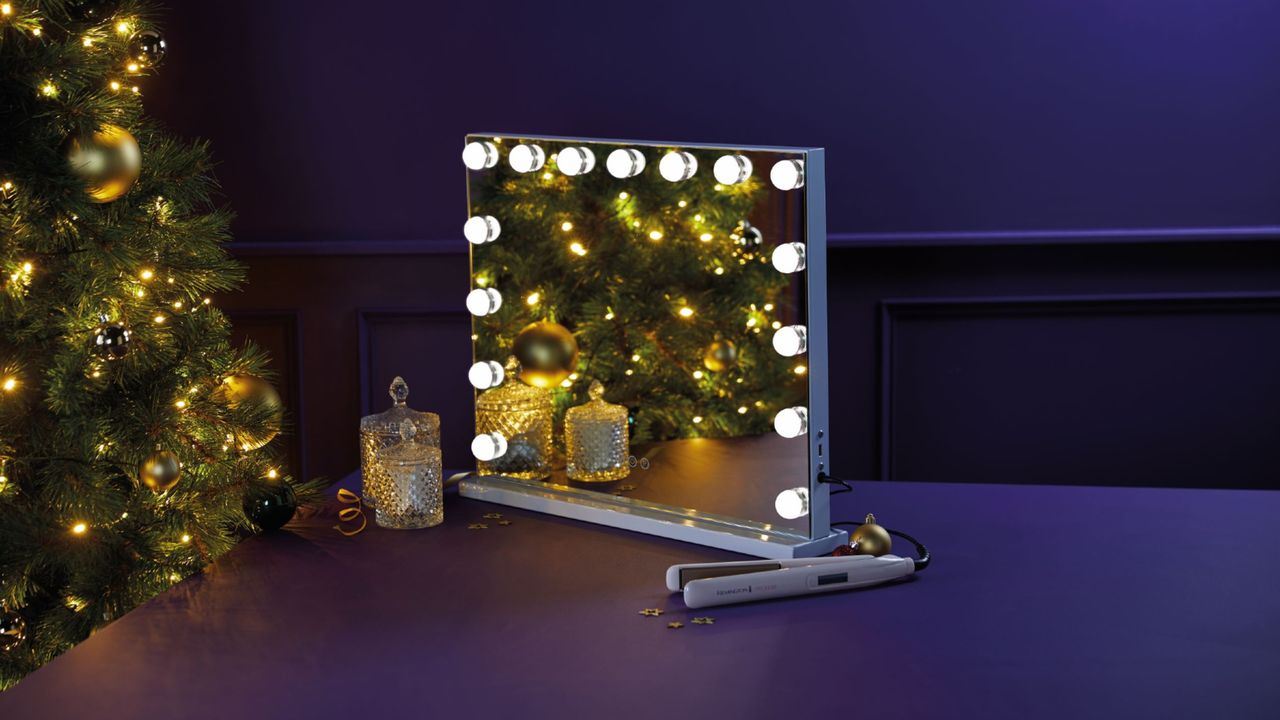 Aldi Hollywood mirror with lights on table next to decorative glass jars, hair straightener and Christmas tree