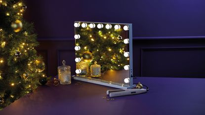 Aldi Hollywood mirror with lights on table next to decorative glass jars and hair straightener