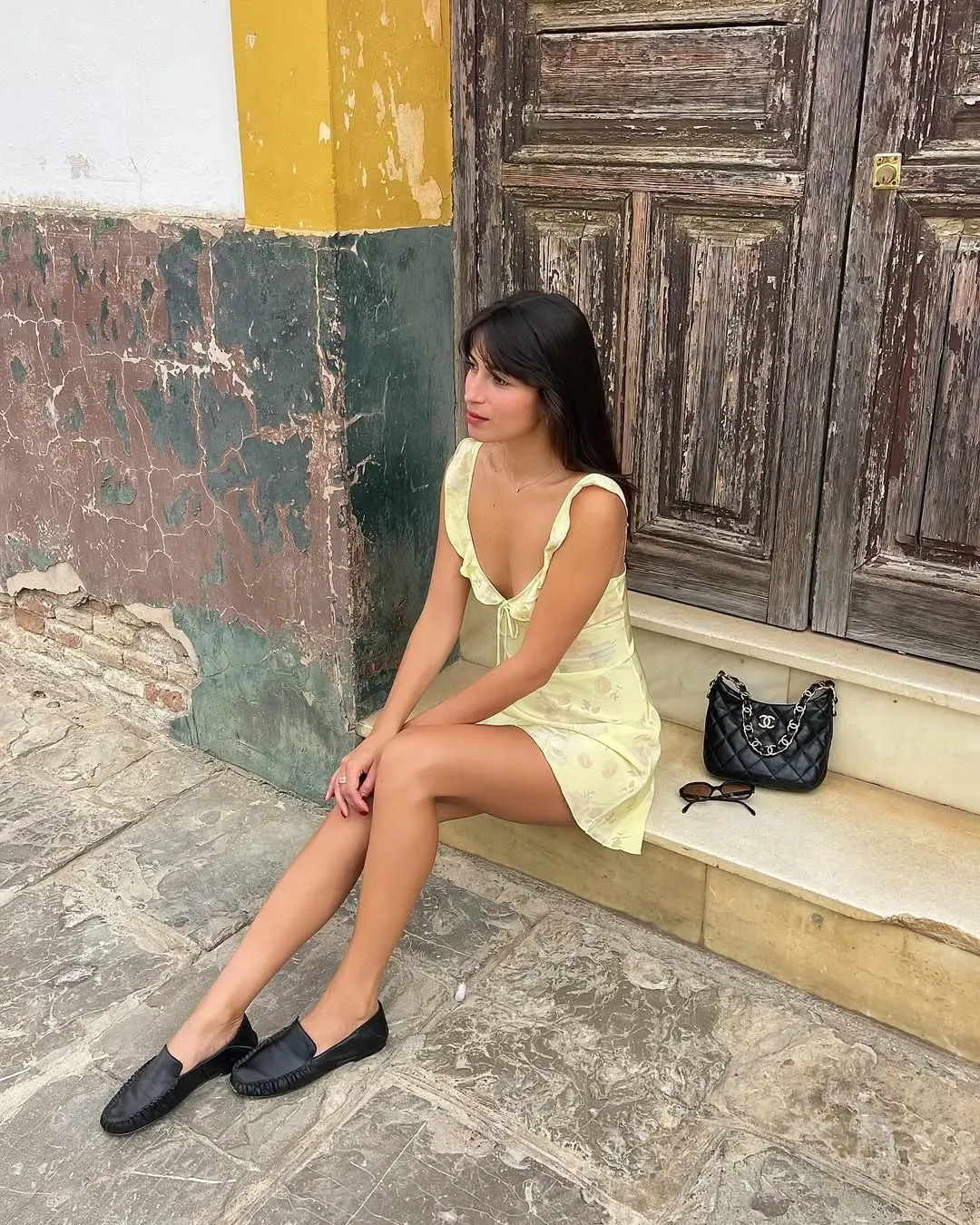 A woman wears black loafers with a yellow dress