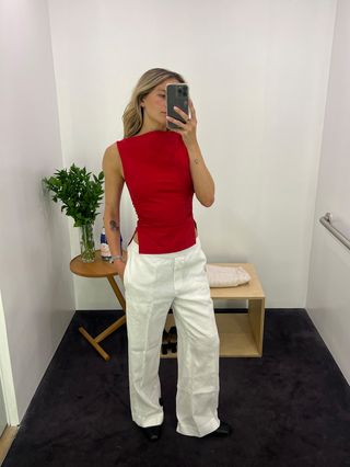 Eliza Huber wears a red crew neck tank top paired with white linen pants at COS.