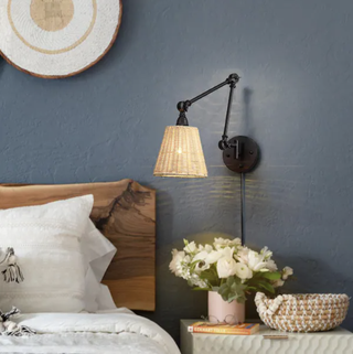 Rattan wall sconce on denim blue bedroom wall