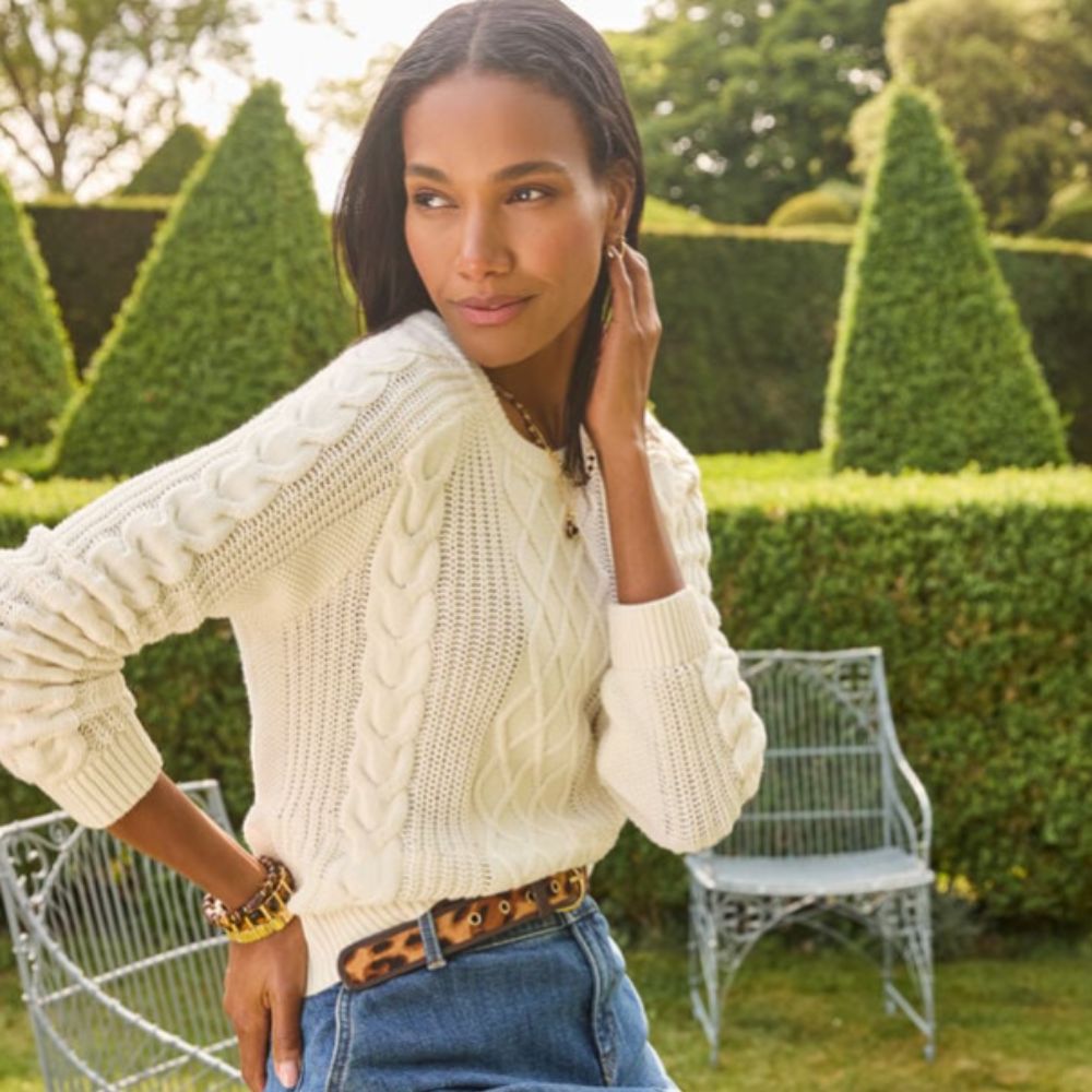 Women standing in garden wearing white Talbots jumper, blue denim skirt, and leopard belt.