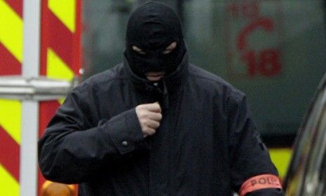 A masked French special intervention police member arrives on the scene during a raid to arrest the suspect in the killing of three children Monday.