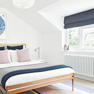 white bedroom with wooden bedframe, radiator and dark window blind