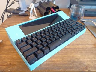 A light blue computer with a black keyboard in the shape of a Tandy Model 100.