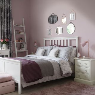 bedroom with pink wall white bed with designed cushions and white shelf