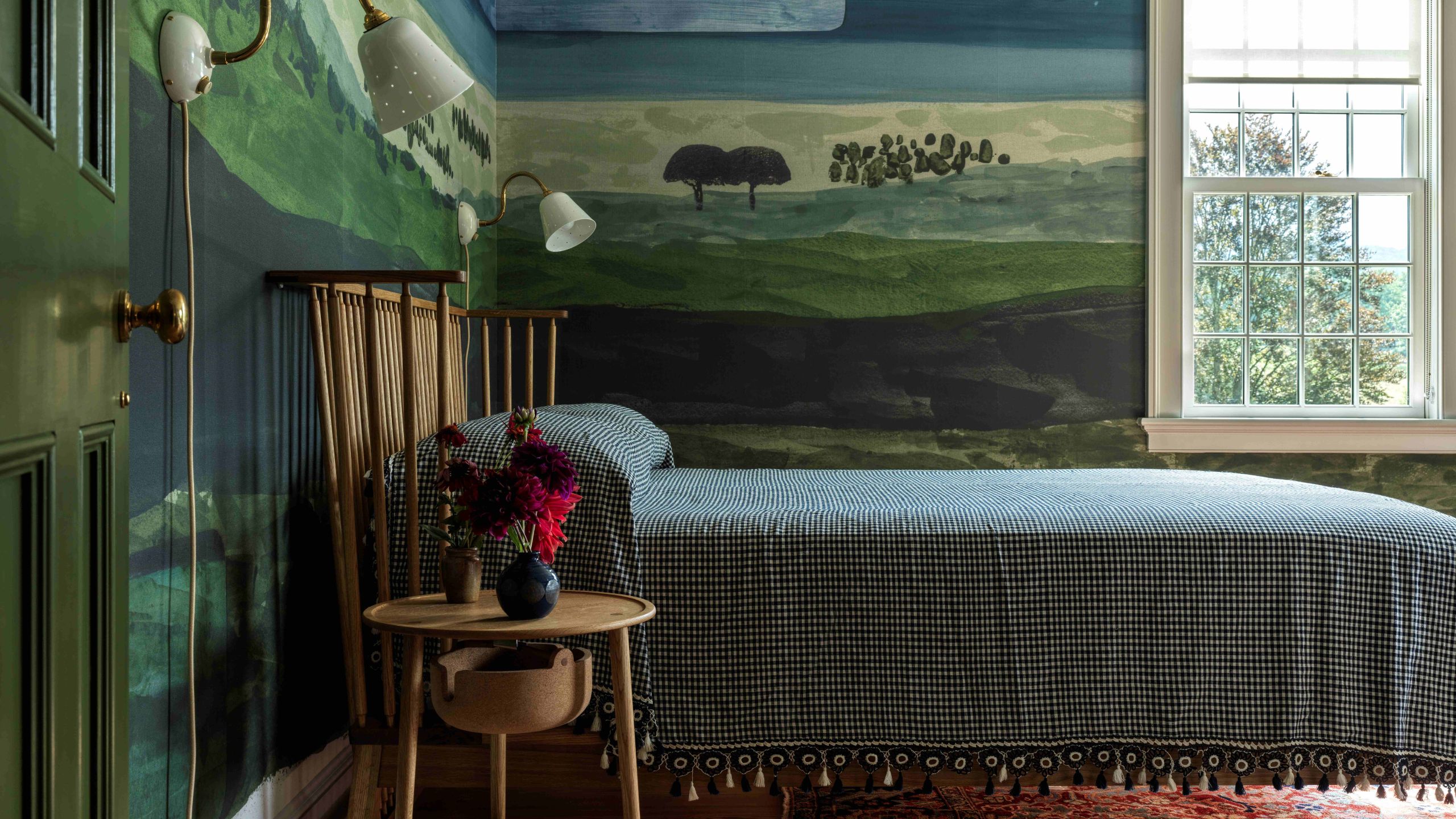 a mural painted bedroom with green and blue tones and wooden simple furniture