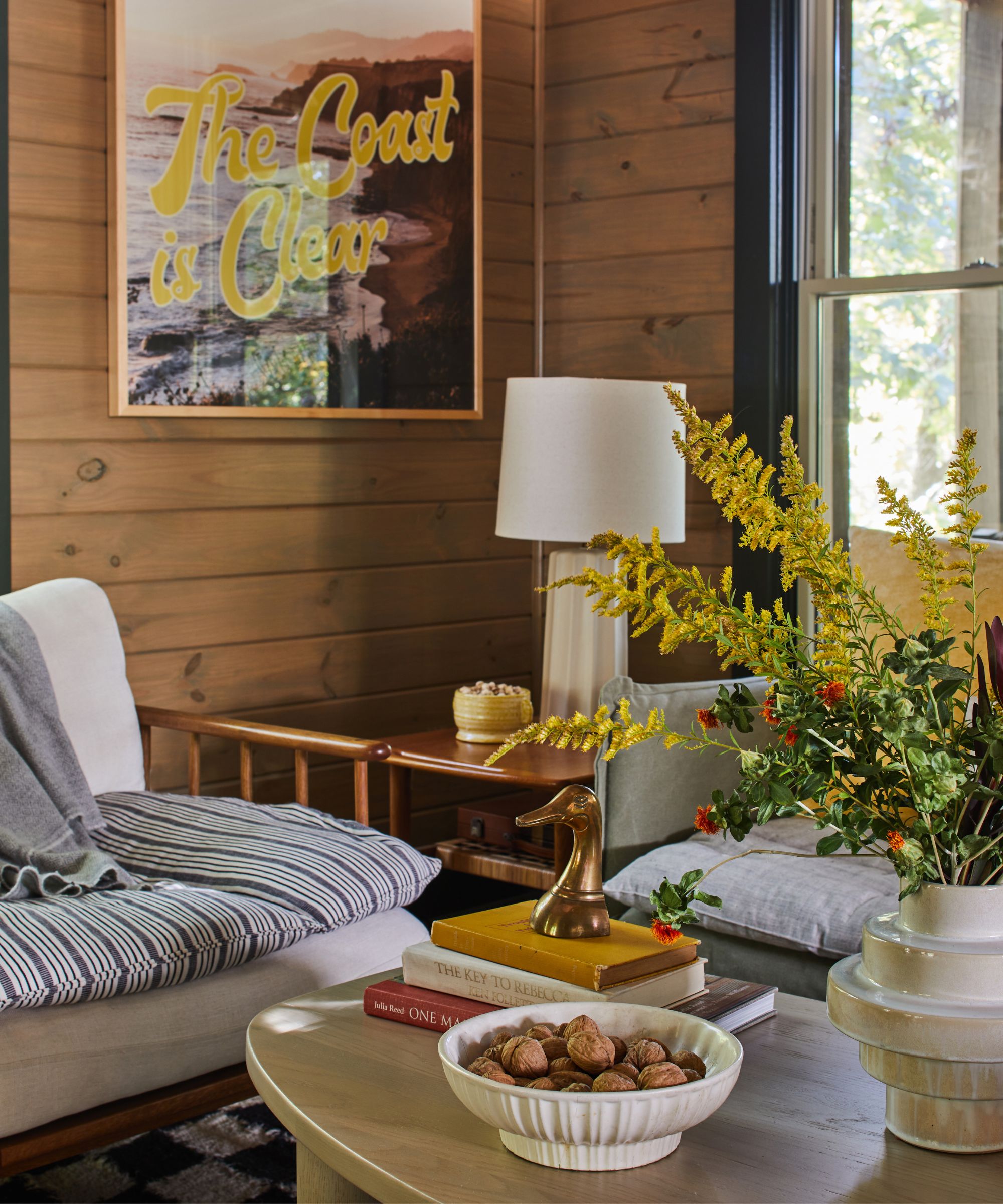 cabin coastal style living room with wooden panelled walls and a neutral wooden sofa with a striped topper