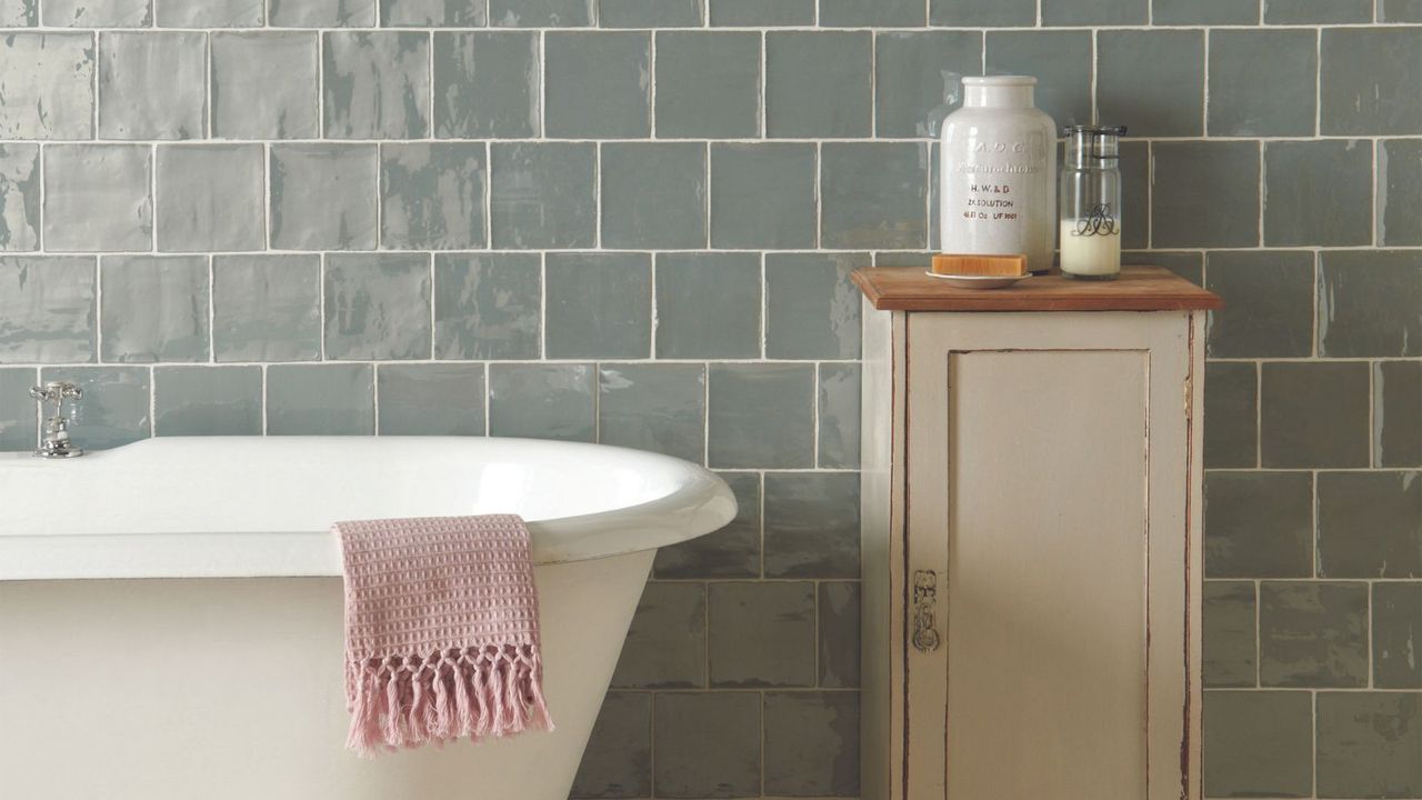 Duck egg colored tiles on a bathroom wall with white grout lines behind a roll edge tub