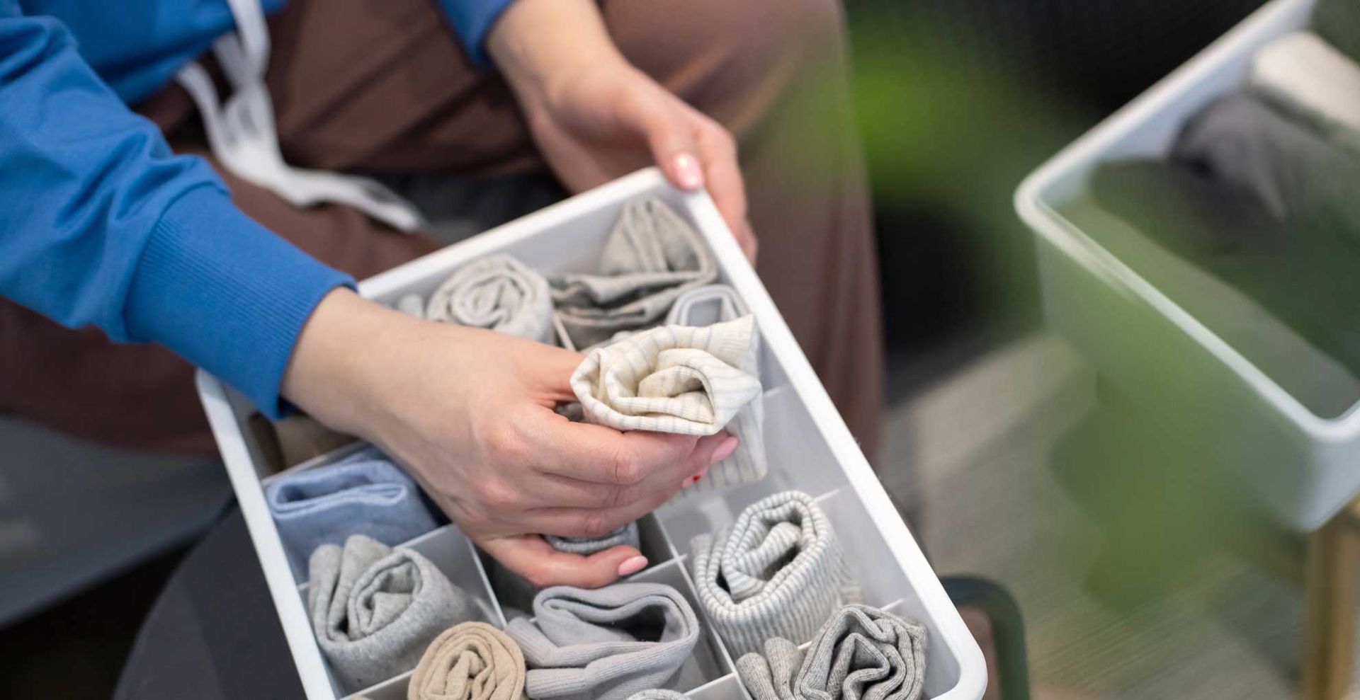 Person neatly folder garments into a basket for storing after finding the motivation to declutter