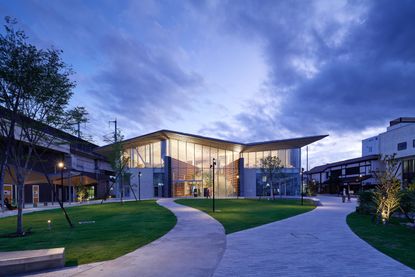 The Nasushiobara library at night which features a kite-style roof and ground to roof panel windows. 