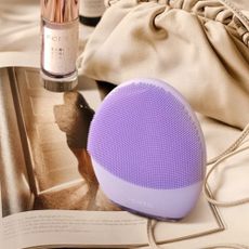 Purple LUNA facial cleanser and serum on magazine next to beige bag