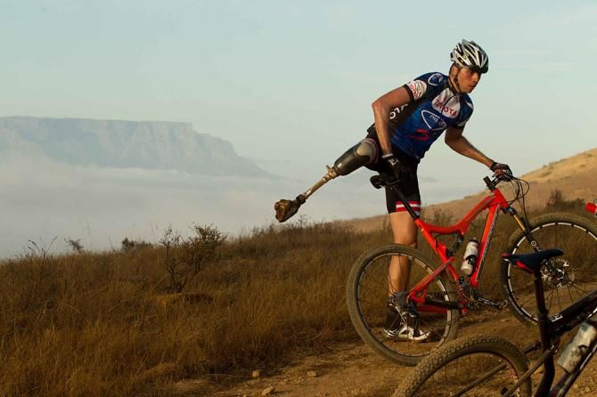 Reuben Van Niekerk dismounts his bicycle to help fellow amputee and team-mate Dane Wilson with a technical problem