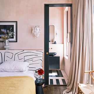 pink bedroom with en suite bathroom, patterned headboard and long curtains