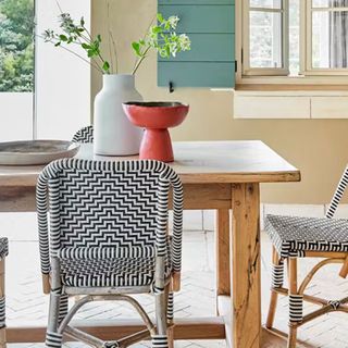 Outdoor dining table on a patio with zig zag rattan seating with walls in Bath Stone by Little Greene