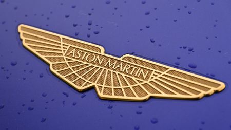 Aston Martin logo in gold against a closeup of a purple car