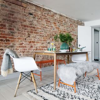 dining space with brick wall and table with white chair