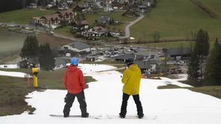 Snow boarders on a small piece of snow as high temperatures wipe out the ski season