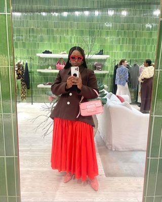 Mecca James-Williams in a brown jacket and a red skirt.