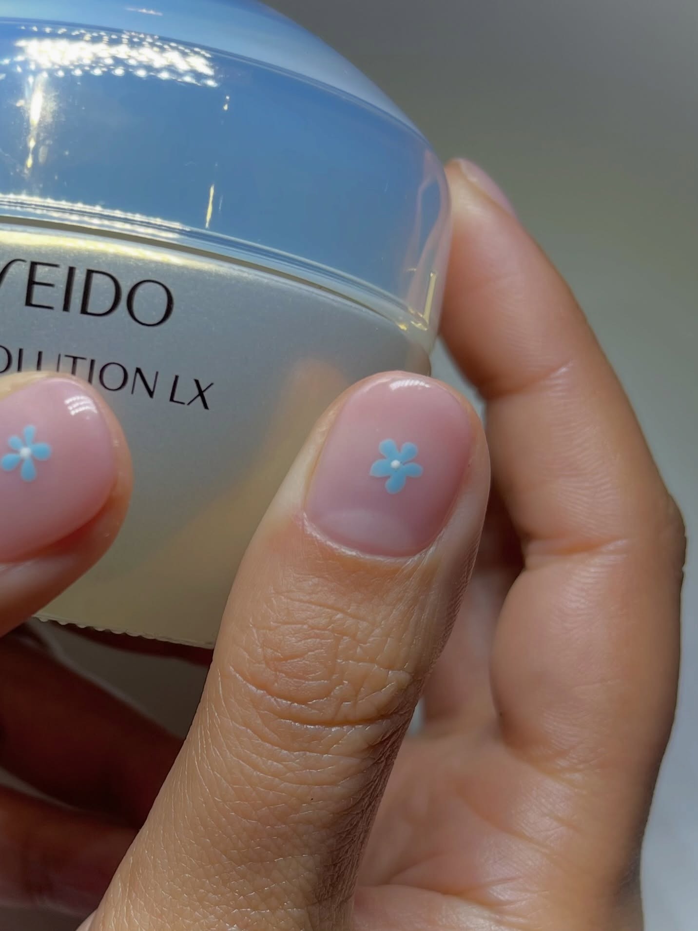 A close-up of a milky nail with a blue micro floral nail design