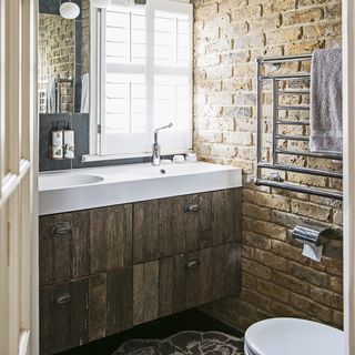 bathroom with exposed brick wall and wooden cabinet