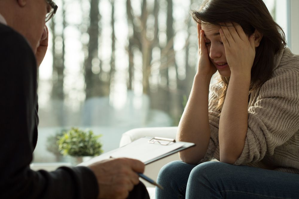 Distressed girl talks to shrink with notepad 