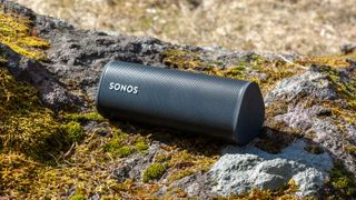 Bluetooth-høyttaleren Sonos Roam på en mosekledd knaus i naturen.