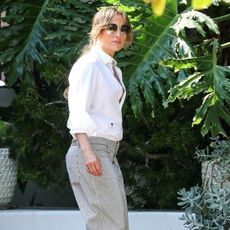 Jennifer Lopez wears a white button down and slacks while touring a house without her wedding ring