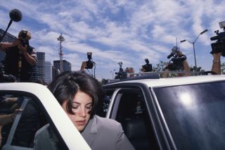 Monica Lewinsky surrounded by photographers as she gets into car.