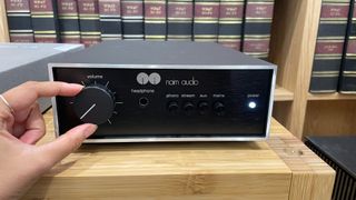 Naim Nait 50 amp on hi-fi rack with hand on volume level