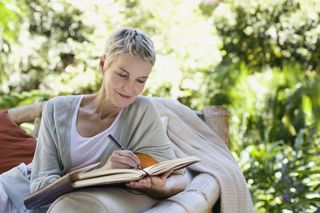 A woman writes in a book journalling