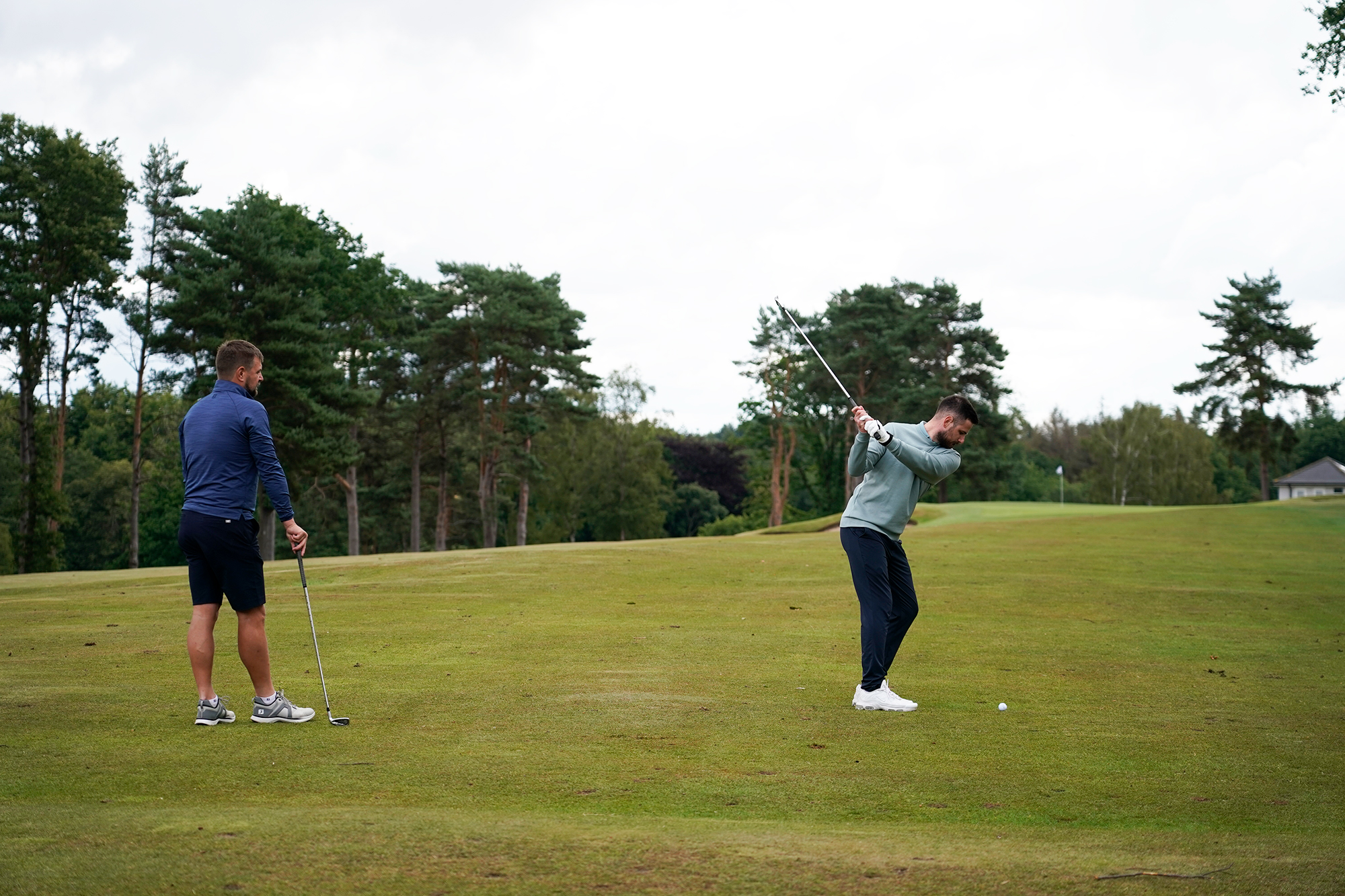 Baz Plummer at the top of his backswing with an iron about to hit into a green at Sand Moor Golf Club