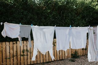 A row of white washing hangs on a washing line, drying in the sun