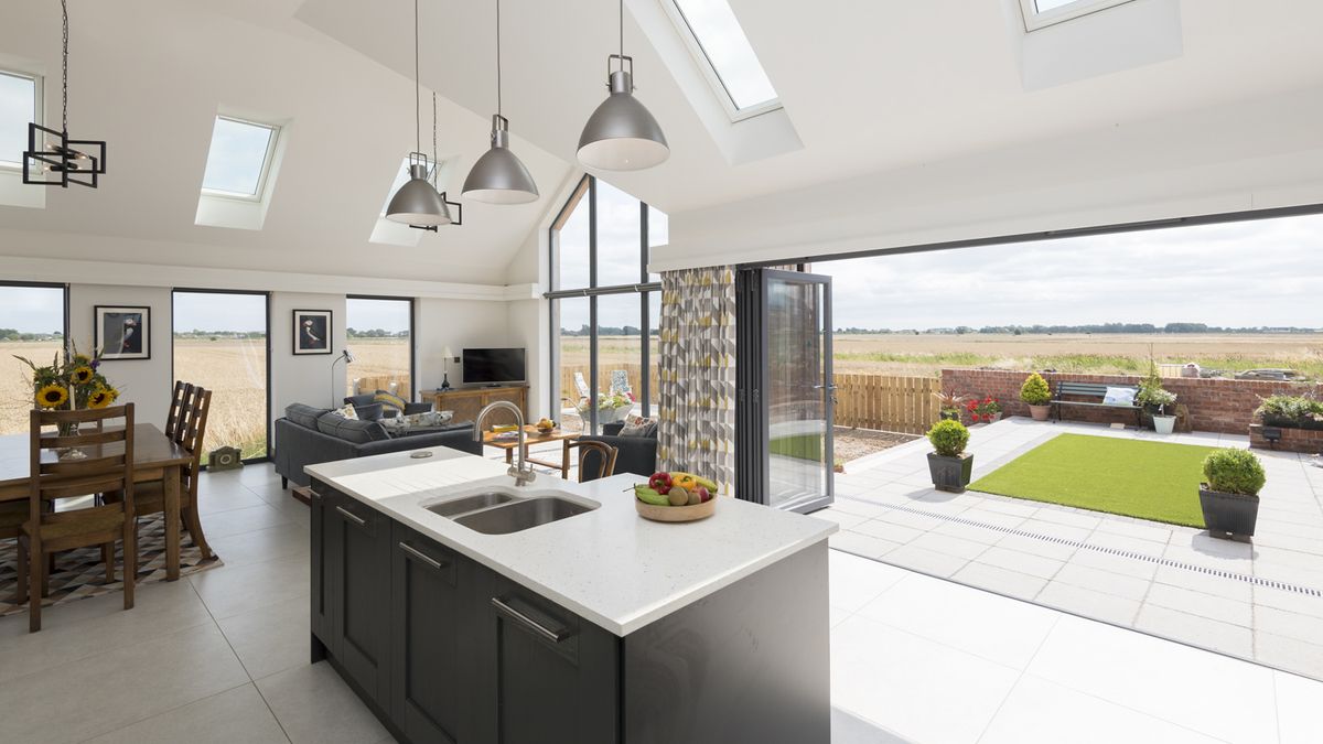 large white kitchen and living room with bifolding doors and rooflights