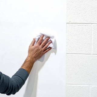 wall lining paper being put up by a male hand in a blue shirt