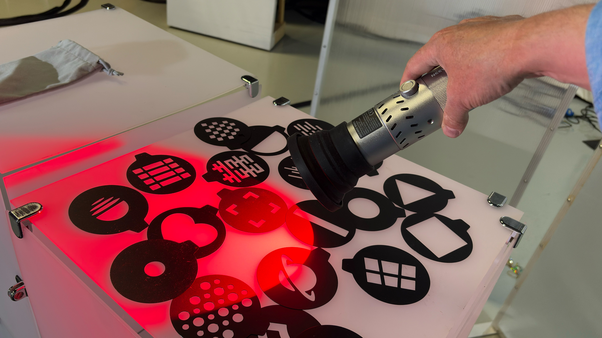 Shot of the Neewer FL20 shining a red spotlight onto the 20 different stencils scattered on a table.